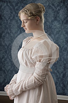 A young Regency woman in a pink dress and pearl necklace