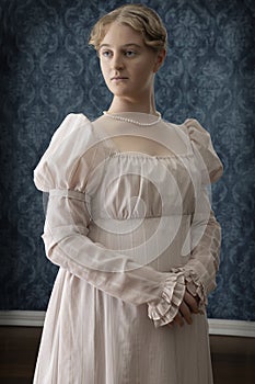 A young Regency woman in a pink dress and pearl necklace