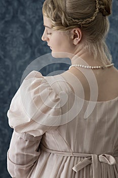 A young Regency woman in a pink dress and pearl necklace