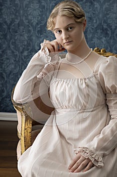 A young Regency woman in a pink dress and pearl necklace