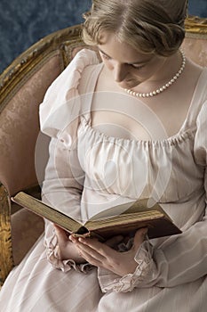 A young Regency woman in a pink dress and pearl necklace