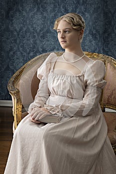 A young Regency woman in a pink dress and pearl necklace