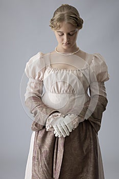 A young Regency woman in a pink dress and pearl necklace