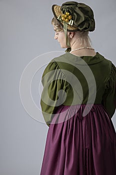 A young Regency woman in a walking dress, gloves, and bonnet
