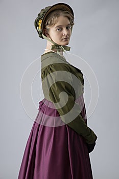 A young Regency woman in a walking dress, gloves, and bonnet