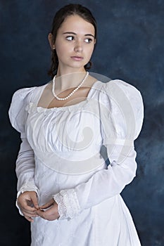 A young Regency woman wearing a white muslin dress and a pearl necklace