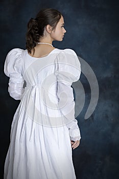 A young Regency woman wearing a white muslin dress and a pearl necklace