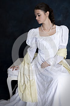 A young Regency woman wearing a white muslin dress and a pearl necklace photo