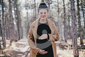 Young regnant woman posing in autumn park