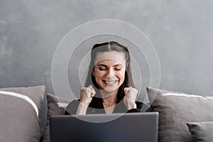 Young rejoiced woman sitting with laptop computer