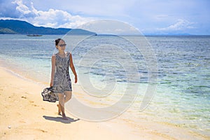 Young relaxed Asian Chinese woman walking on Thailand island beach with amazing beautiful turquoise color water under a summer blu