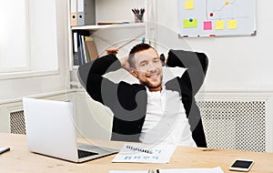 Young relaxed businessman with laptop in modern white office