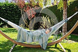 Young relaxed girl sleeping peacefully in hammock in garden at home