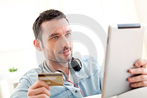 Young relaxed man buying music on tablet