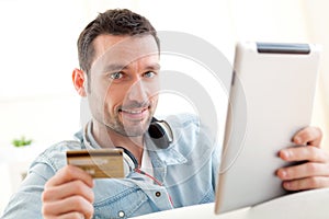 Young relaxed man buying music on tablet