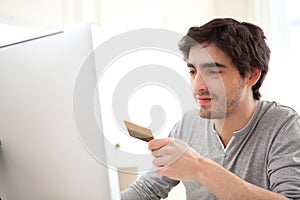Young relaxed man paying online with his credit card