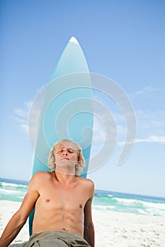 Young relaxed man sitting on the beach while sunbathing