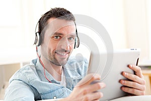 Young relaxed man using tablet in a sofa