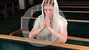 Young religious devoted woman praying in baptist church. Faithful catholic at european cathedral: inside of holy place