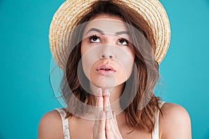 Young religious girl in straw hat praying for a vacation