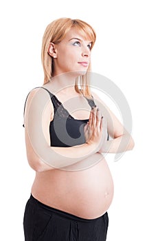 Young religious pregnant woman praying with palms together