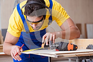 The young repairman carpenter working cutting wood on circular saw