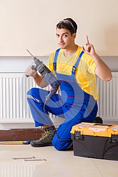 The young repairman contractor repairing heating panel