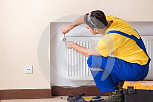 The young repairman contractor repairing heating panel