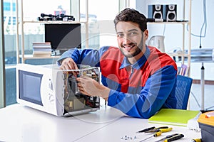 The young repairman fixing and repairing microwave oven