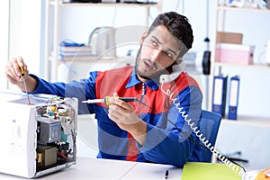 The young repairman fixing and repairing microwave oven