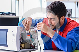 The young repairman fixing and repairing microwave oven