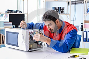 The young repairman fixing and repairing microwave oven