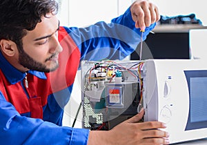 Young repairman fixing and repairing microwave oven