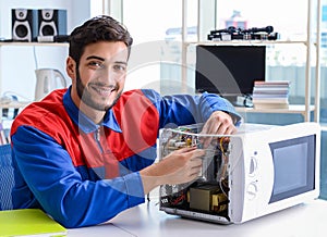 Young repairman fixing and repairing microwave oven