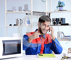 Young repairman fixing and repairing microwave oven