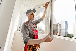 Young repairman fixing window frame in room at daytime