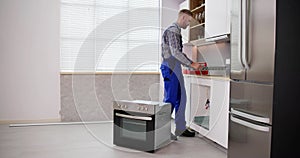 Young Repairman Installing Induction Cooker