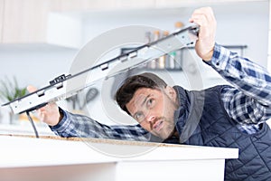 young repairman installing induction cooker in kitchen