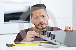 young repairman installing induction cooker in kitchen