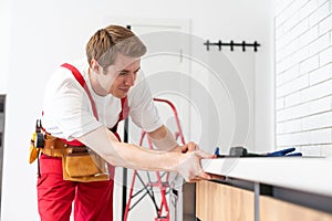 Young Repairman Installing Induction Cooker In Kitchen.
