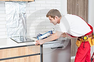 Young Repairman Installing Induction Cooker In Kitchen.