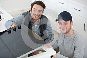 young repairman installing induction cooker in kitchen