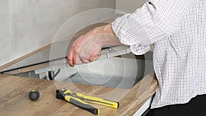 A young repairman installs a black induction hob in a modern white Scandinavian style kitchen