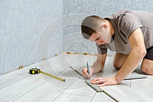 Young repairman is markup a wooden panel with a pencil and ruler before cutting