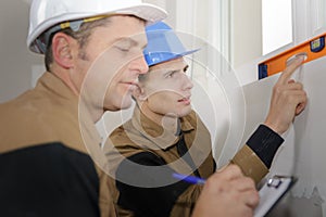 Young repairman measuring with builder level