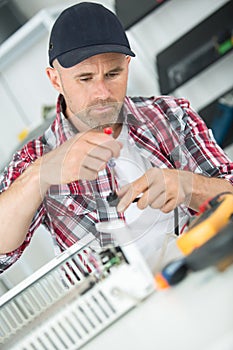 Young repairman in overall repairing appliances