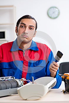 Young repairman repairing air-conditioner at warranty center