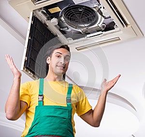 Young repairman repairing ceiling air conditioning unit