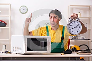 The young repairman repairing microwave in service centre