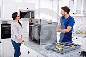 Young Repairman Repairing Oven On Kitchen Worktop photo